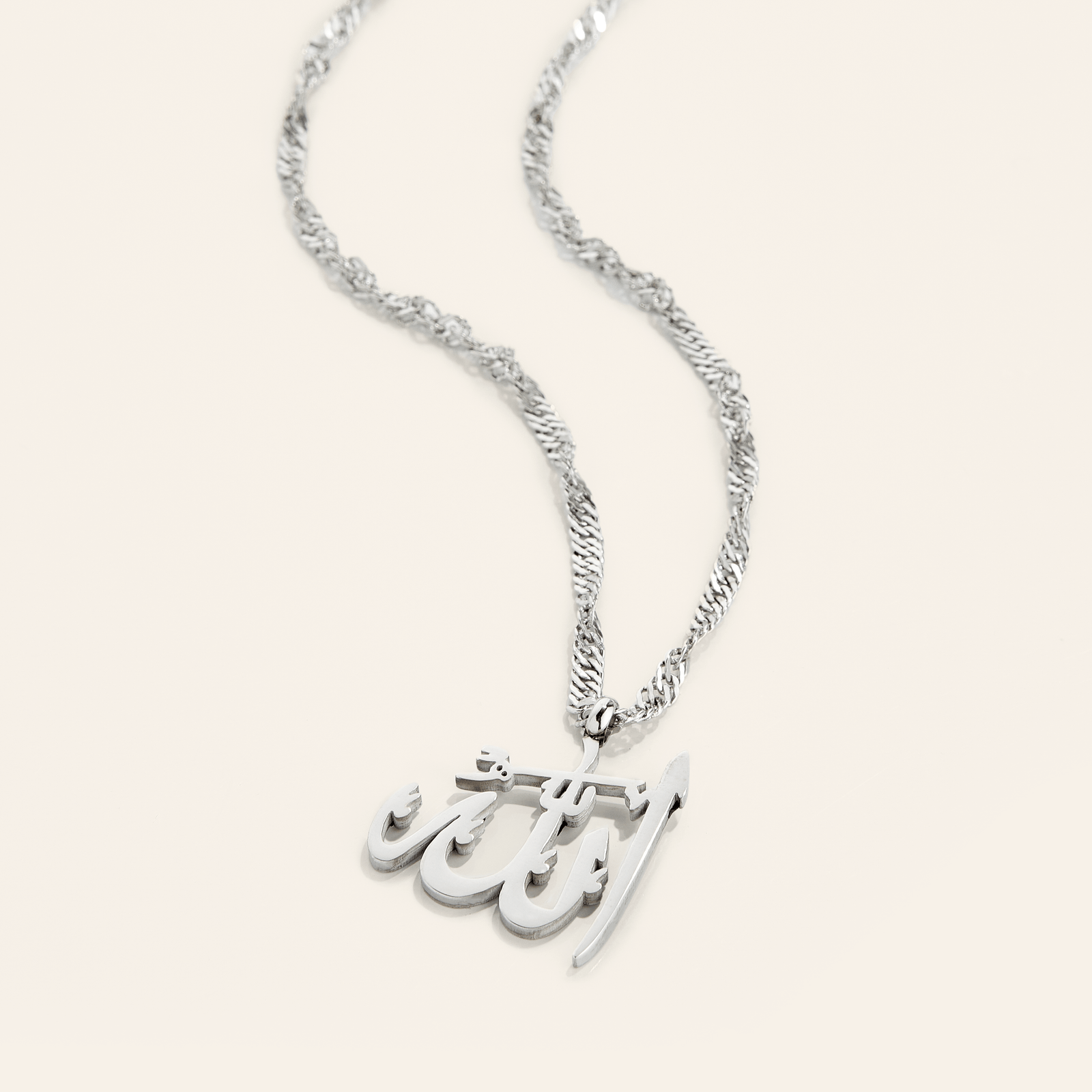 Photo of a silver necklace with a pendant that features the Arabic Calligraphy for Allah.