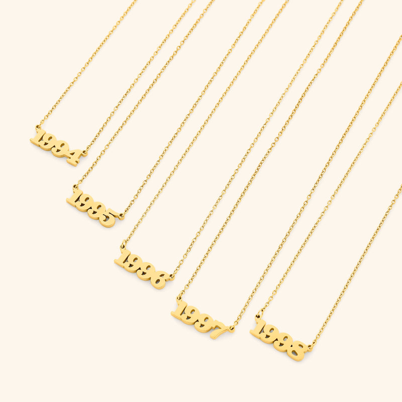 Gold necklace with english number pendants representing birth years on a white background