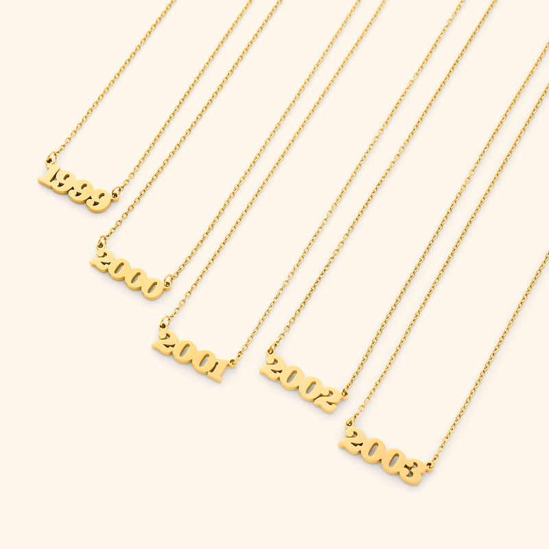 Gold necklace with english number pendants representing birth years on a light background