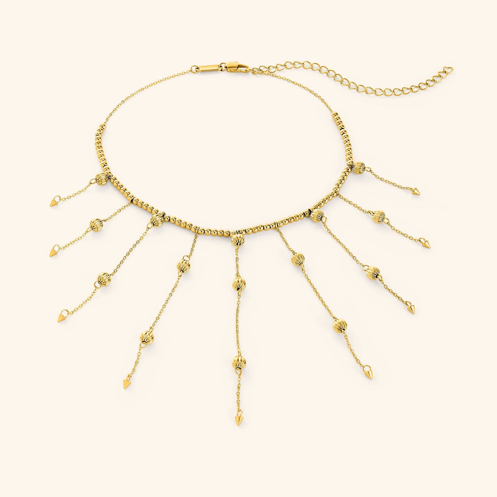Flat lay of an 18k gold plated necklace that  features a dotted chain all along the necklace and drops each lariat 3.5 inches down with delicate, evenly spaced orbs