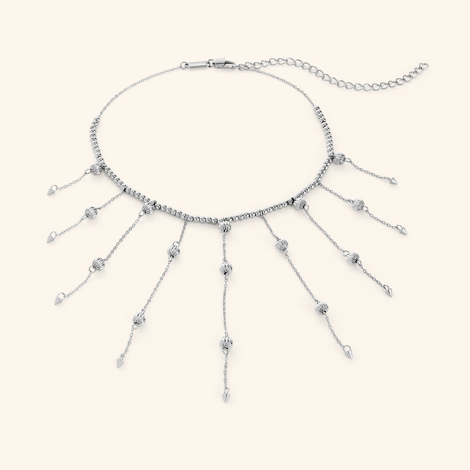 Flat lay of a silver necklace that  features a dotted chain all along the necklace and drops each lariat 3.5 inches down with delicate, evenly spaced orbs