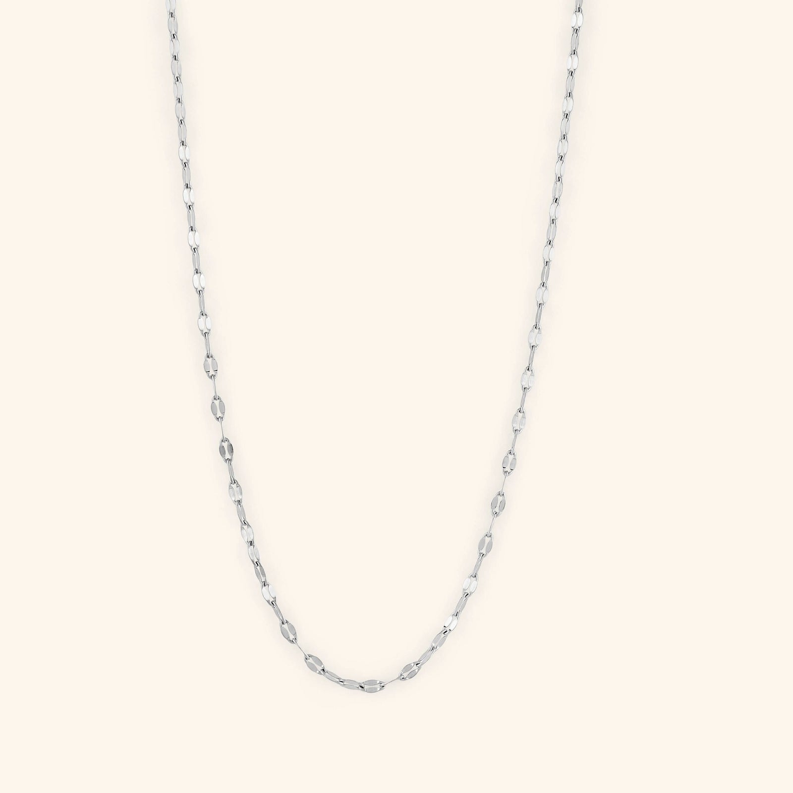 Photo of a minimalistic silver necklace against a light background.