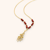 18k gold plated chain necklace with a detailed flower stem pendant and reddish-brown tube beads.