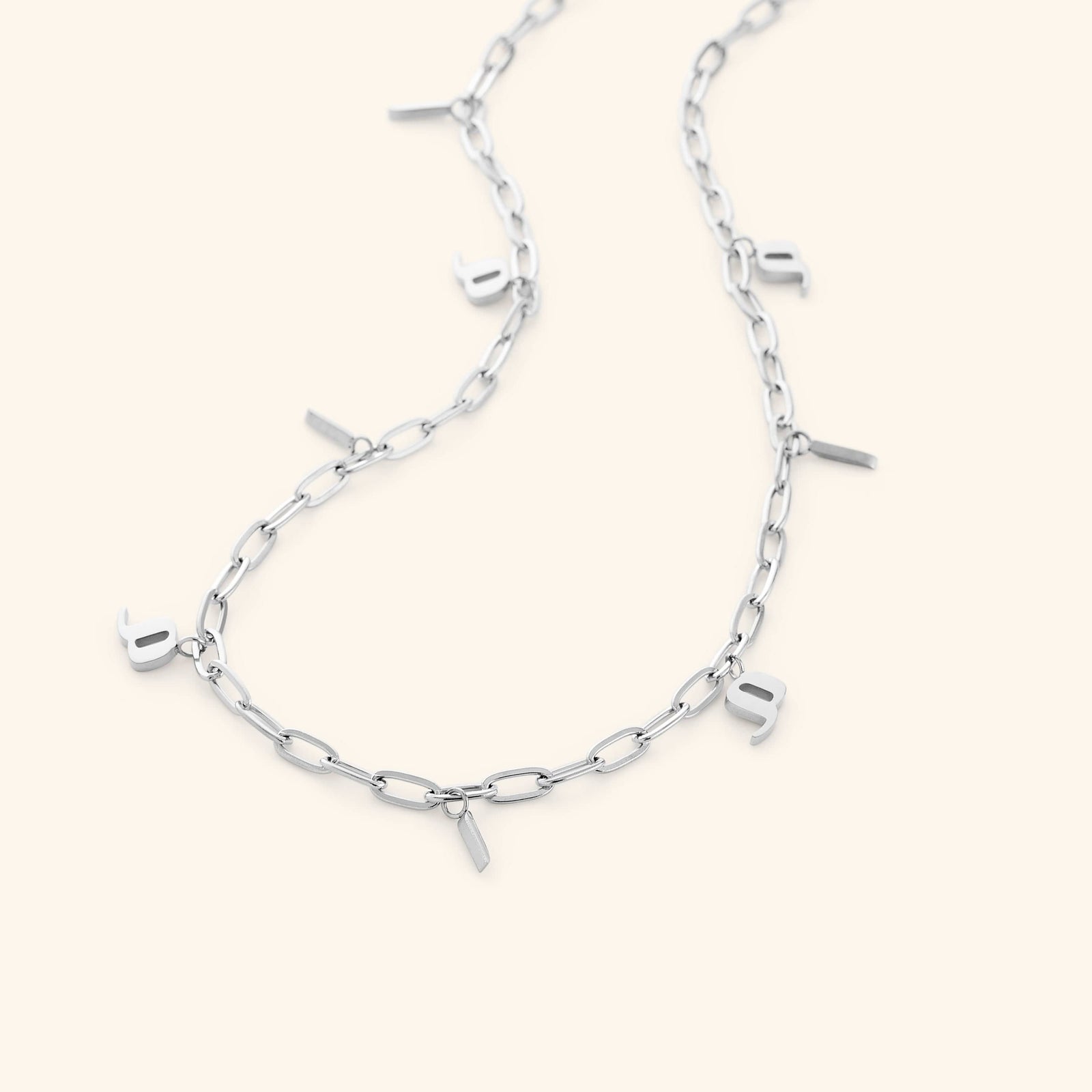 The Mama Charm Necklace in a polished silver finish, displaying the repeating Arabic "Mama" charms along the sleek oval link chain, offering a modern and minimalist aesthetic.