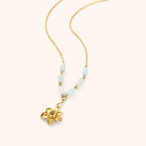 18k gold plated chain necklace with a detailed flower pendant and pale blue tube beads.