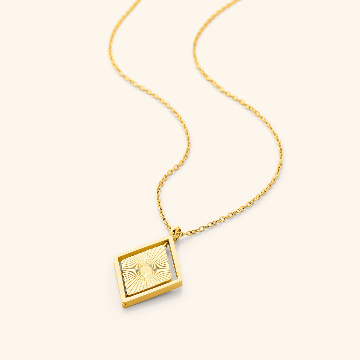 Photo of the 18k gold plated necklace that features a design inspired by the radiant sun rays, this brand new piece features a solid encasing holding a spinning diamond-shaped pendant.