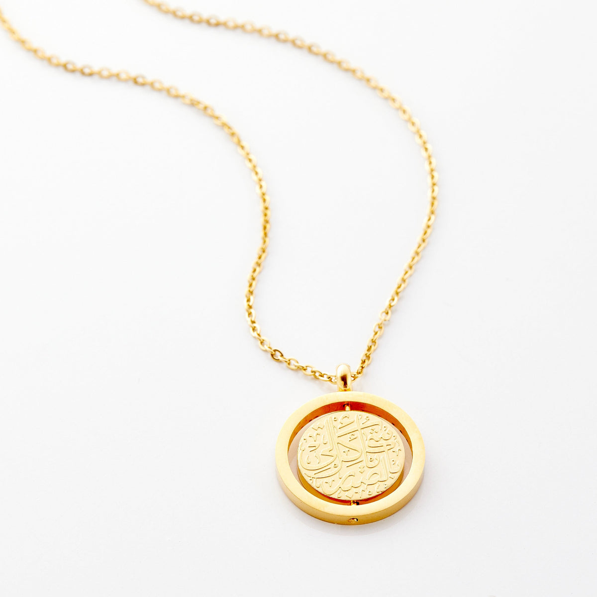Photo of an 18k gold plated necklace that features the Arabic calligraphy engraving for "Everything Comes with Patience".