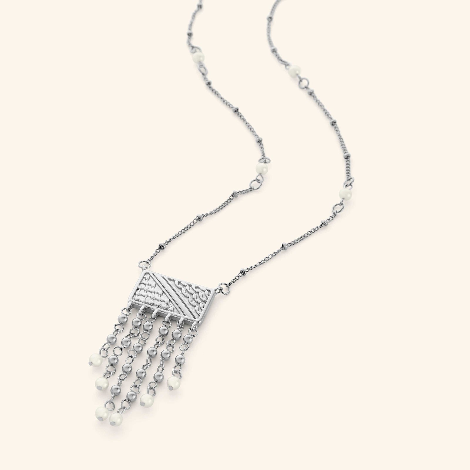 Silver necklace featuring  a rectangular plate that is engraved with the patterns of the Palestinian keffiyeh, and then trailed with chains that are finished with pearl orbs. The necklace is finished with pearl orbs along the chain.
