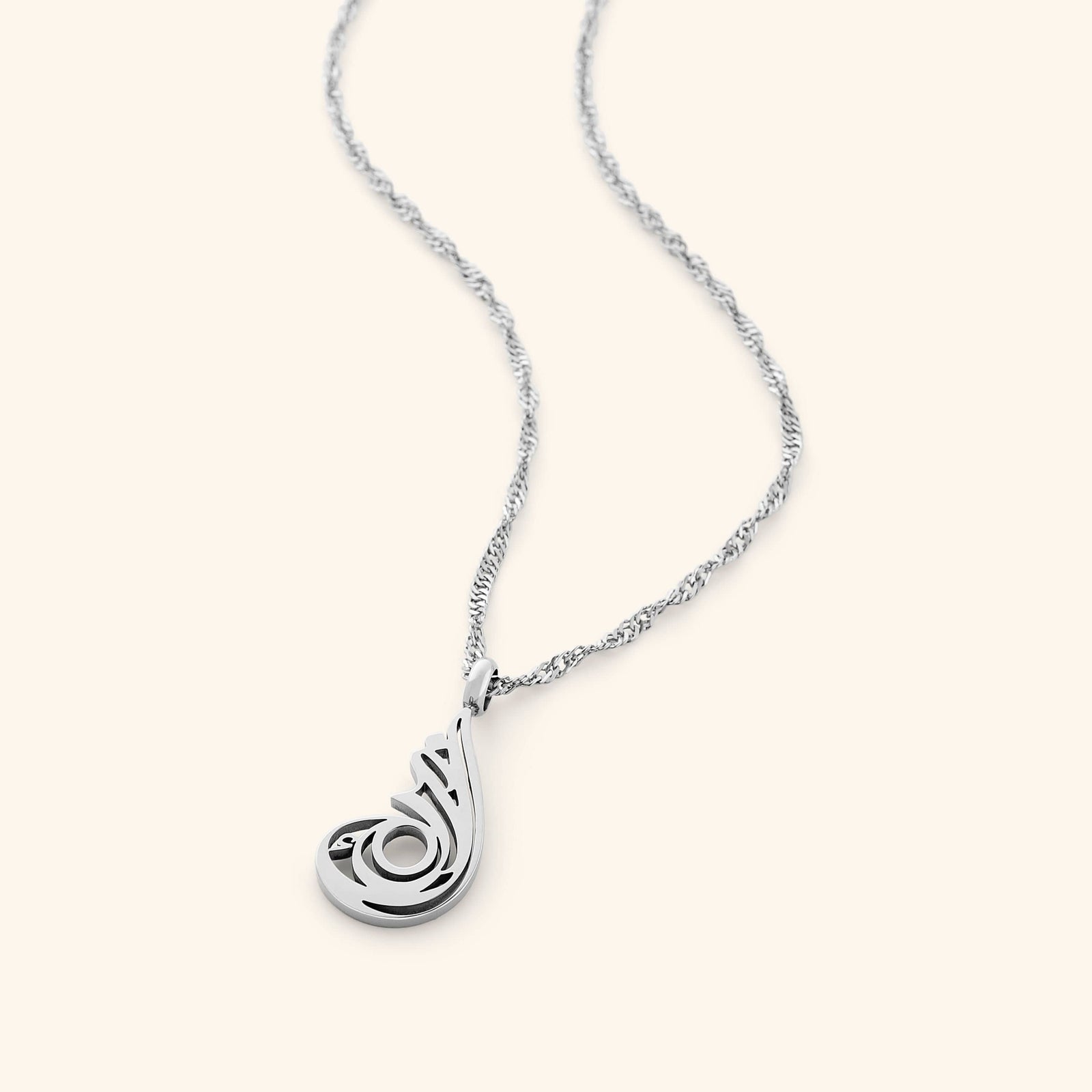 The image shows a delicate silver chain necklace. The chain has a twisted or rope-like texture. The pendant is an abstract, stylized design,  with intricate cut-out details.