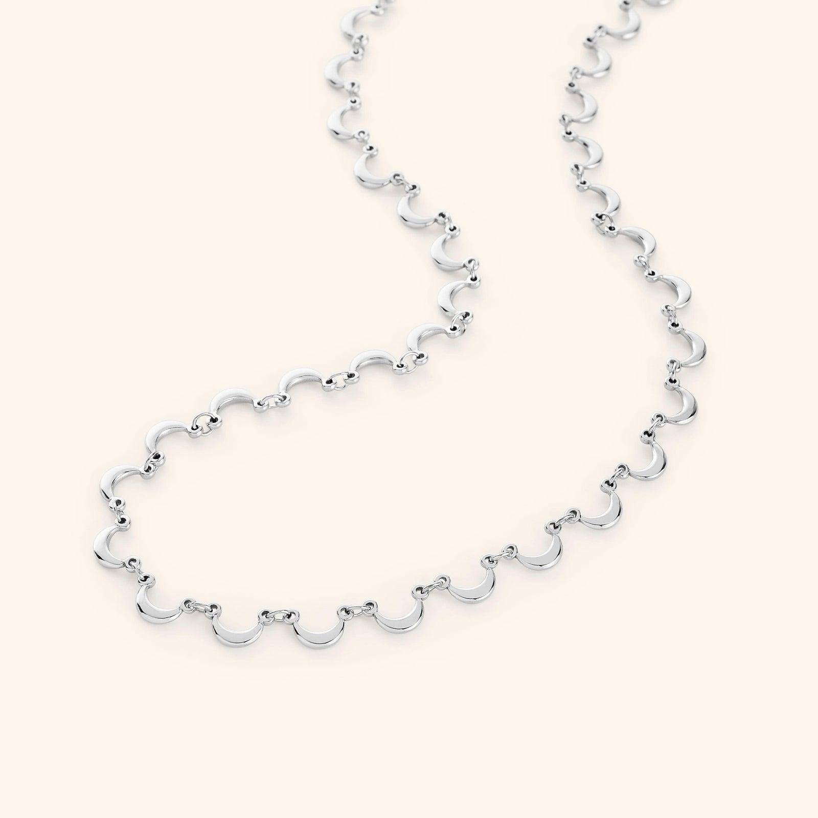 The Skyfall Necklace in a polished silver finish, showcasing a continuous chain of crescent-shaped charms that elegantly mimic the phases of the moon.