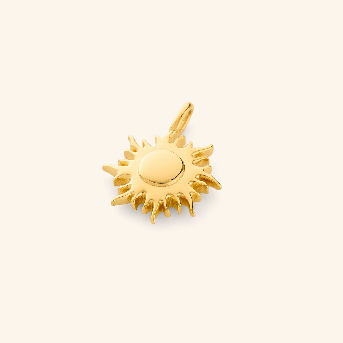 Gold sunshine charm with pointed rays and a smooth round center, photographed flat lay against a soft cream background.