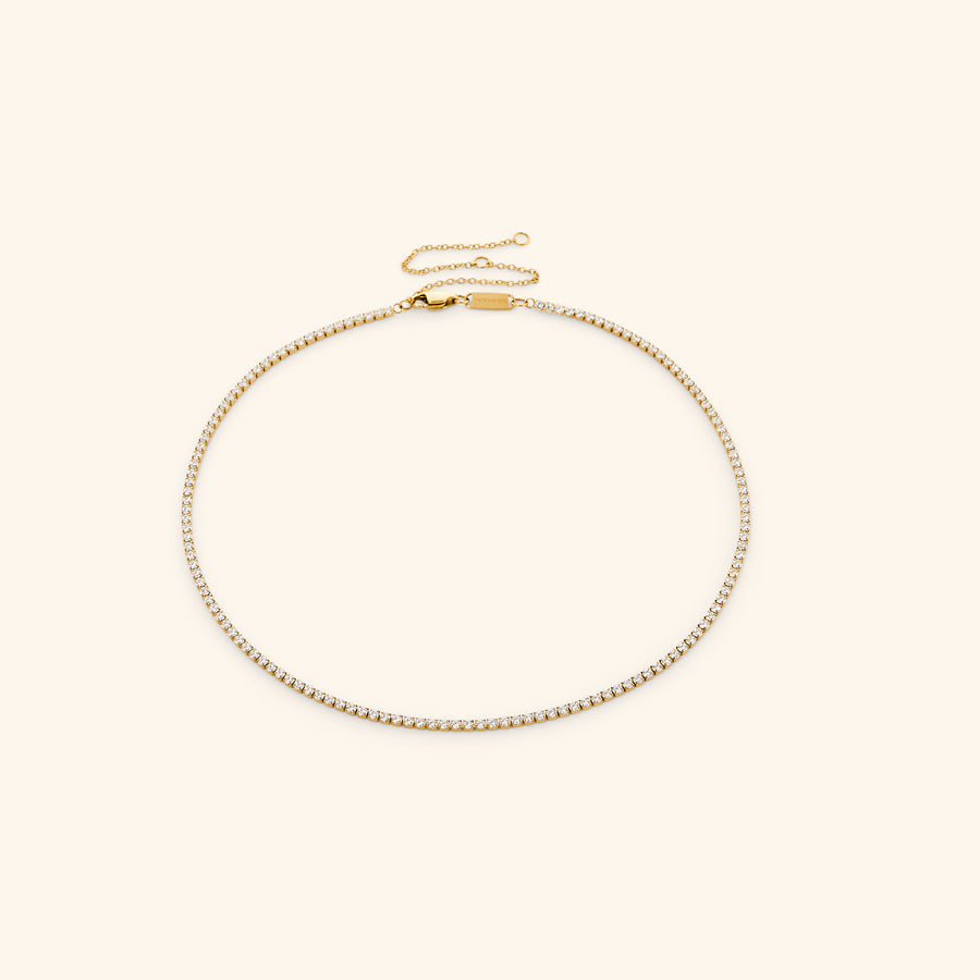 18k gold-plated Tennis Necklace featuring a continuous strand of round clear crystals with an adjustable extension chain.