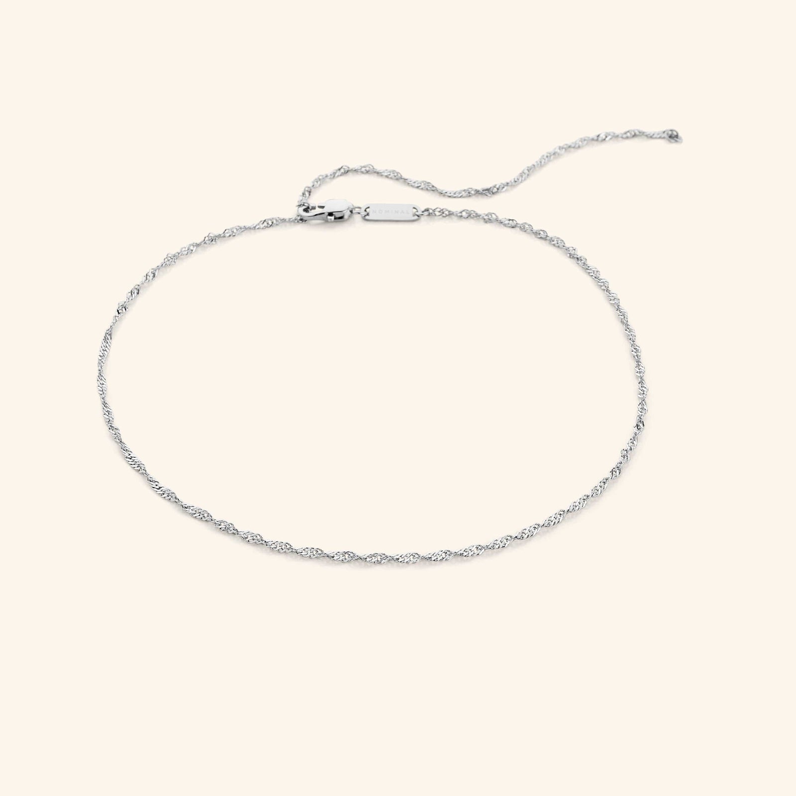 Silver twisted chain choker displayed against a neutral beige background.