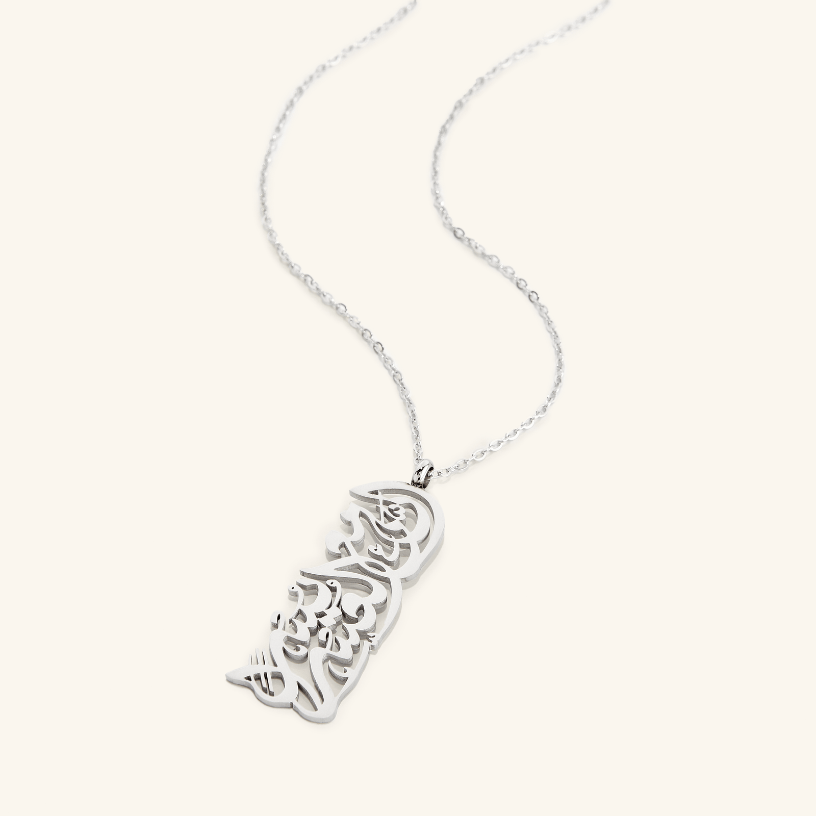 The "With Hardship Comes Ease" Calligraphy Necklace in a polished silver finish. The rectangular pendant displays the same Arabic verse, offering a sleek and timeless design.