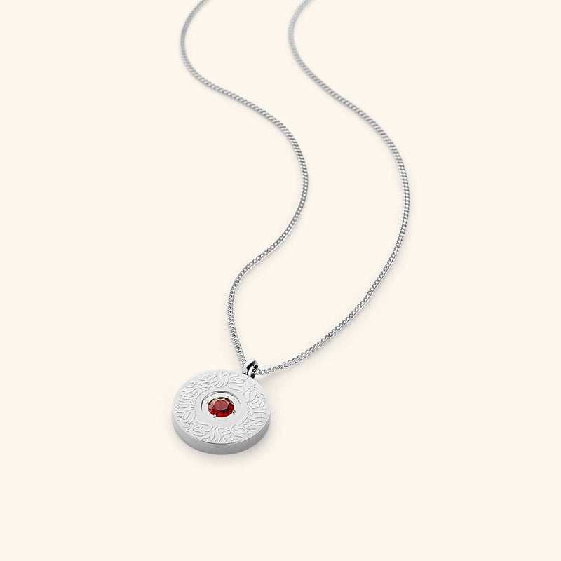 A round silver medallion pendant on a silver chain pimage_ featuring a red agate stone in the center with surrounding engraved Arabic calligraphy.