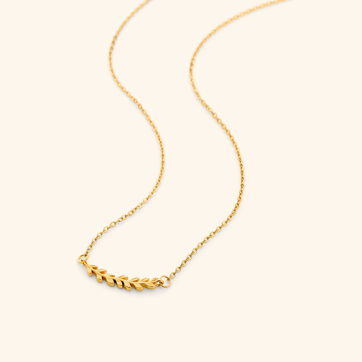 The Weaving Olive Branch Necklace by Nominal, featuring a delicate 18k gold-plated chain with a curved pendant of intricately sculpted olive leaves, displayed on an off-white background.