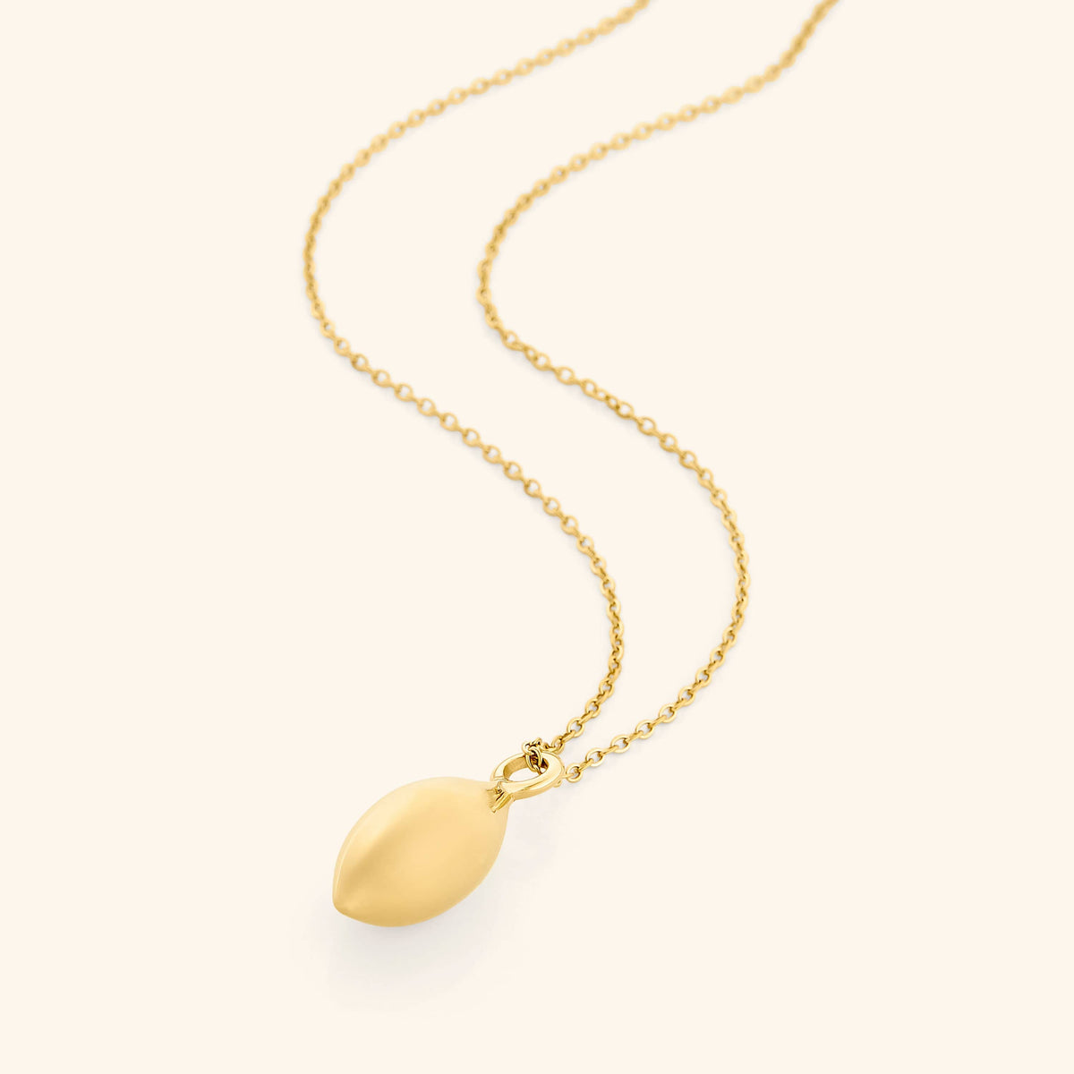 Flat lay of an 18k gold plated necklace with a pendant that is made in the actual spherical shape of an olive and inspired by the beautiful olive trees of Palestine