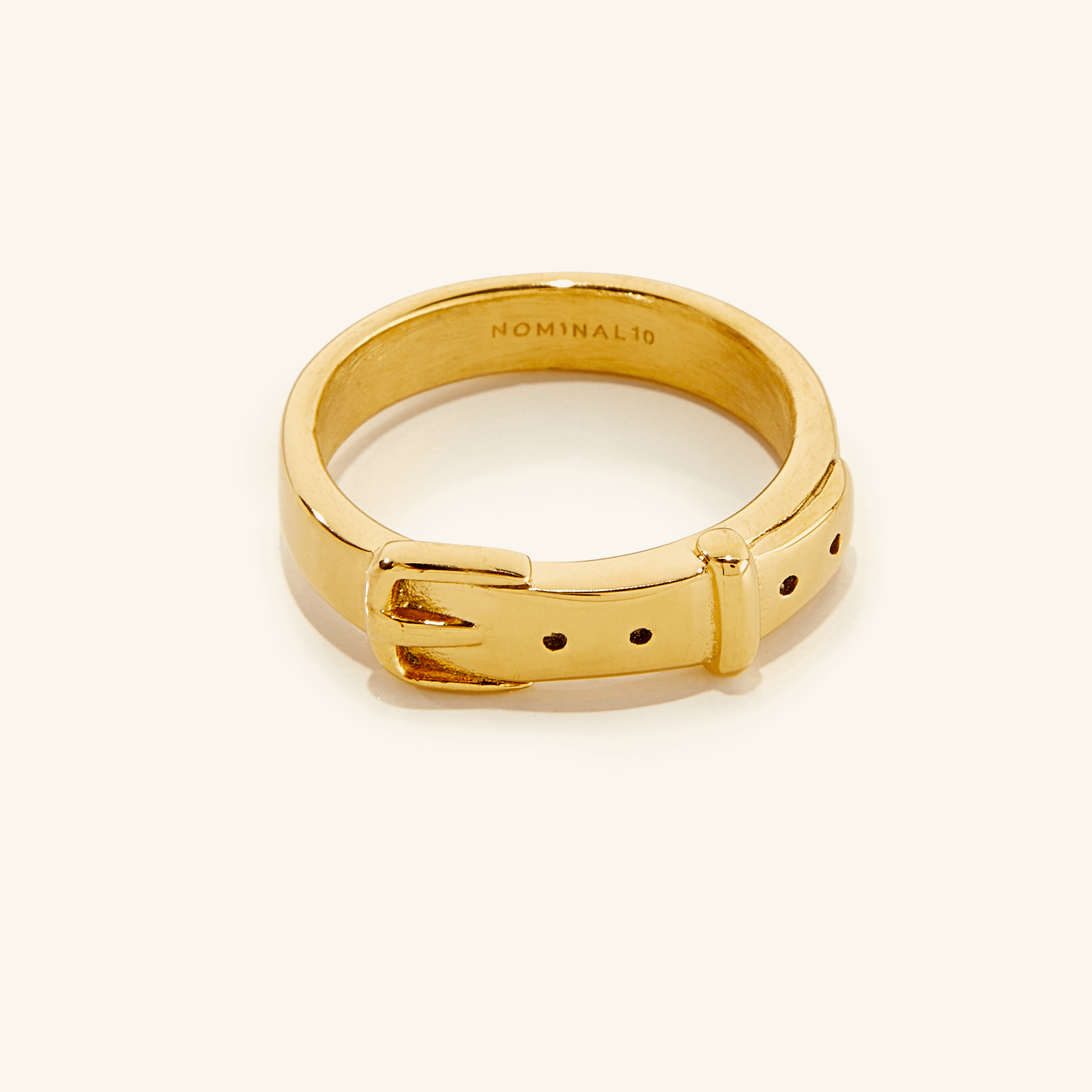 Gold ring with buckle design on a light background.