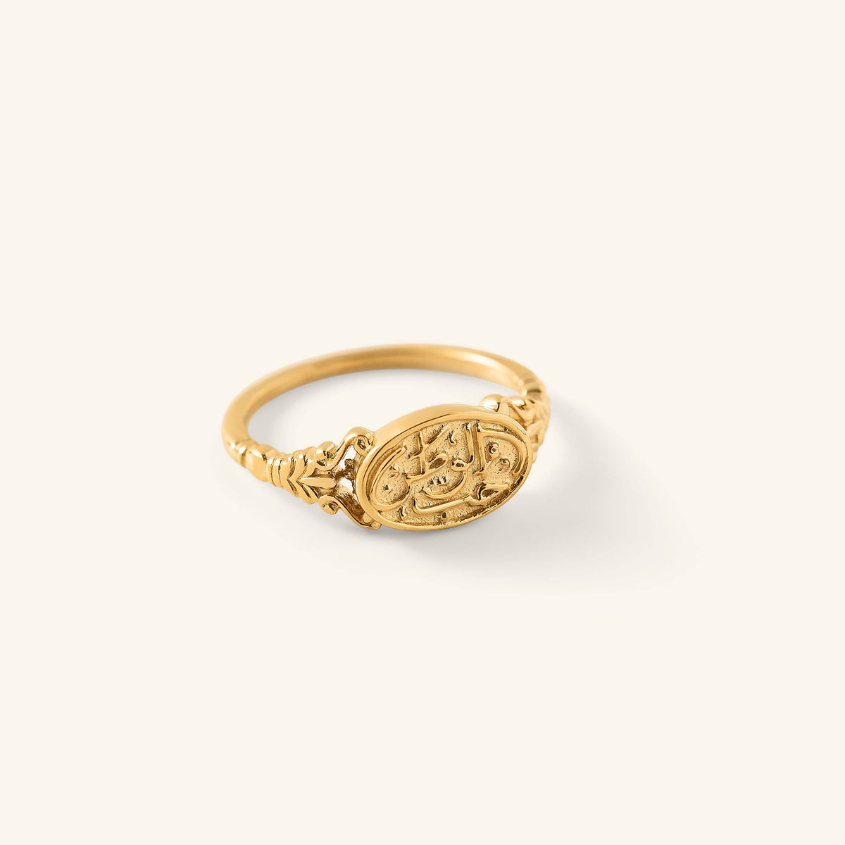 Gold Homeland Ring with an oval face engraved in Arabic calligraphy and a decorative band, shown against a neutral background.