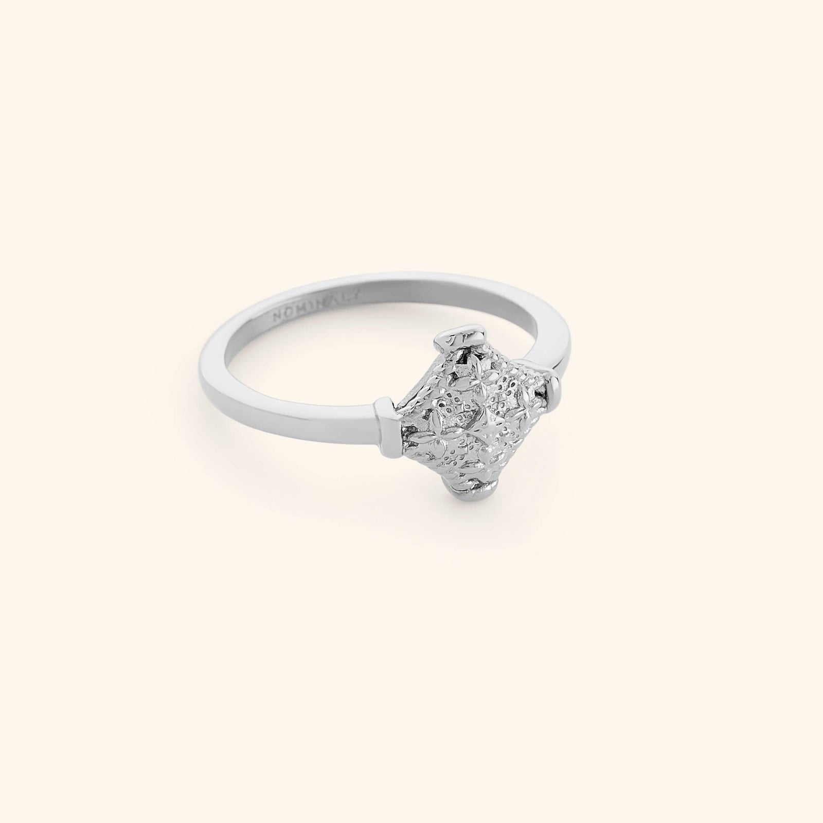 Silver kitework ring featuring a raised, textured centerpiece.
