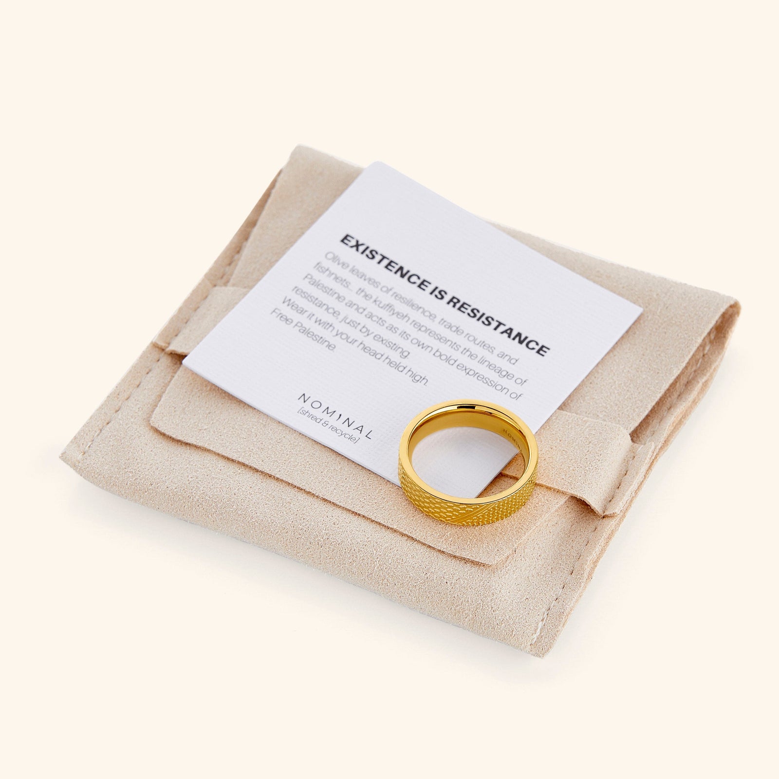 The Keffiyeh Ring with an engraved keffiyeh-inspired pattern, placed on a beige suede pouch and a card reading “Existence is Resistance.”