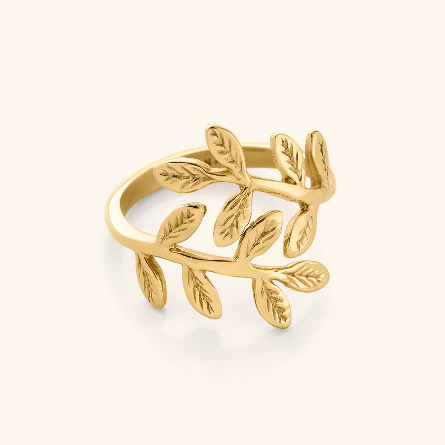 Close-up of a gold ring shaped like intertwining olive branches with detailed leaves engraved on each side.