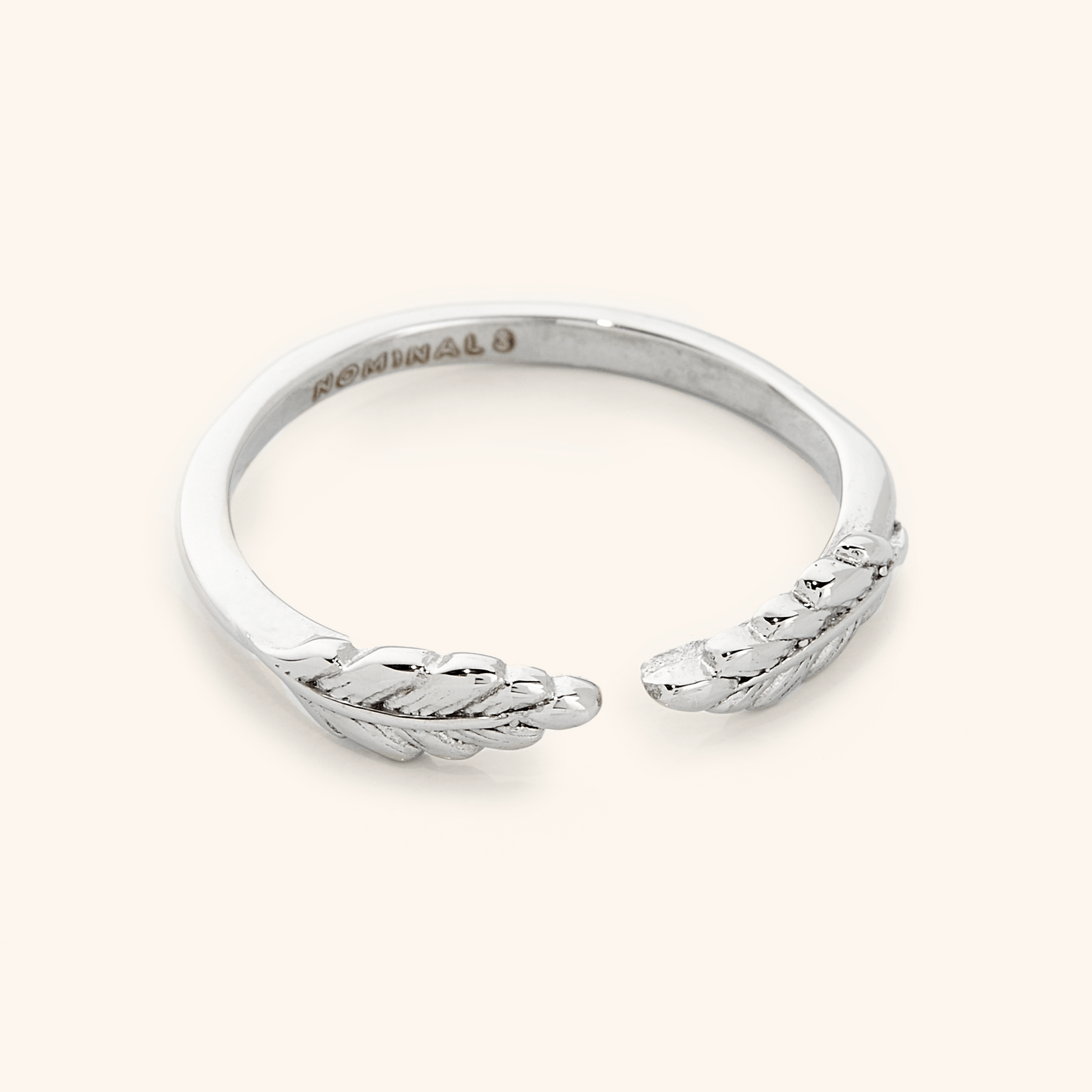 The ring displayed in a polished silver finish, highlighting the intricate leaf details and the open band structure.