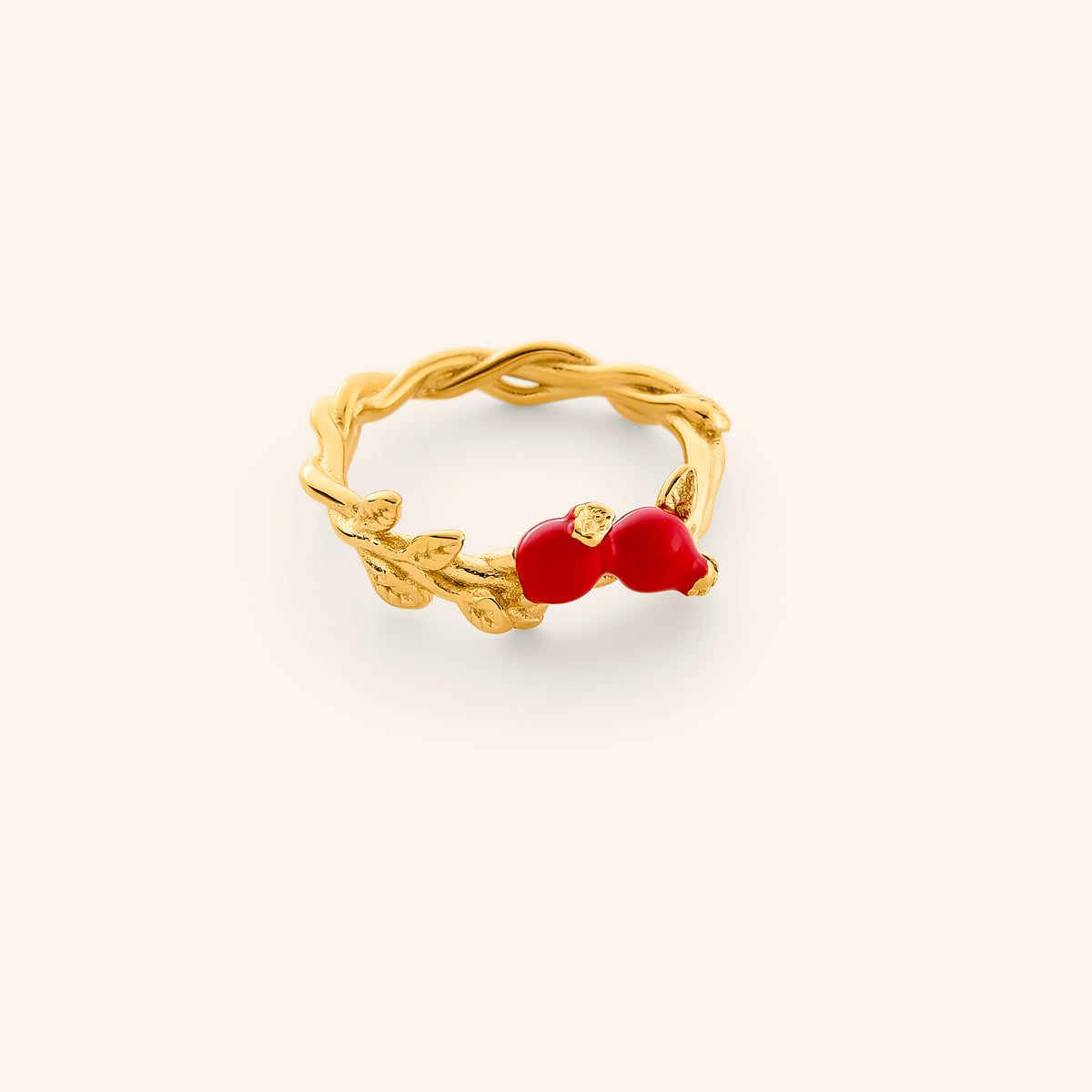 The Pomegranate Vine Ring by Nominal, featuring an 18k gold-plated twisted vine band accented with golden leaves and two vibrant red pomegranate fruit charms, displayed on an off-white background