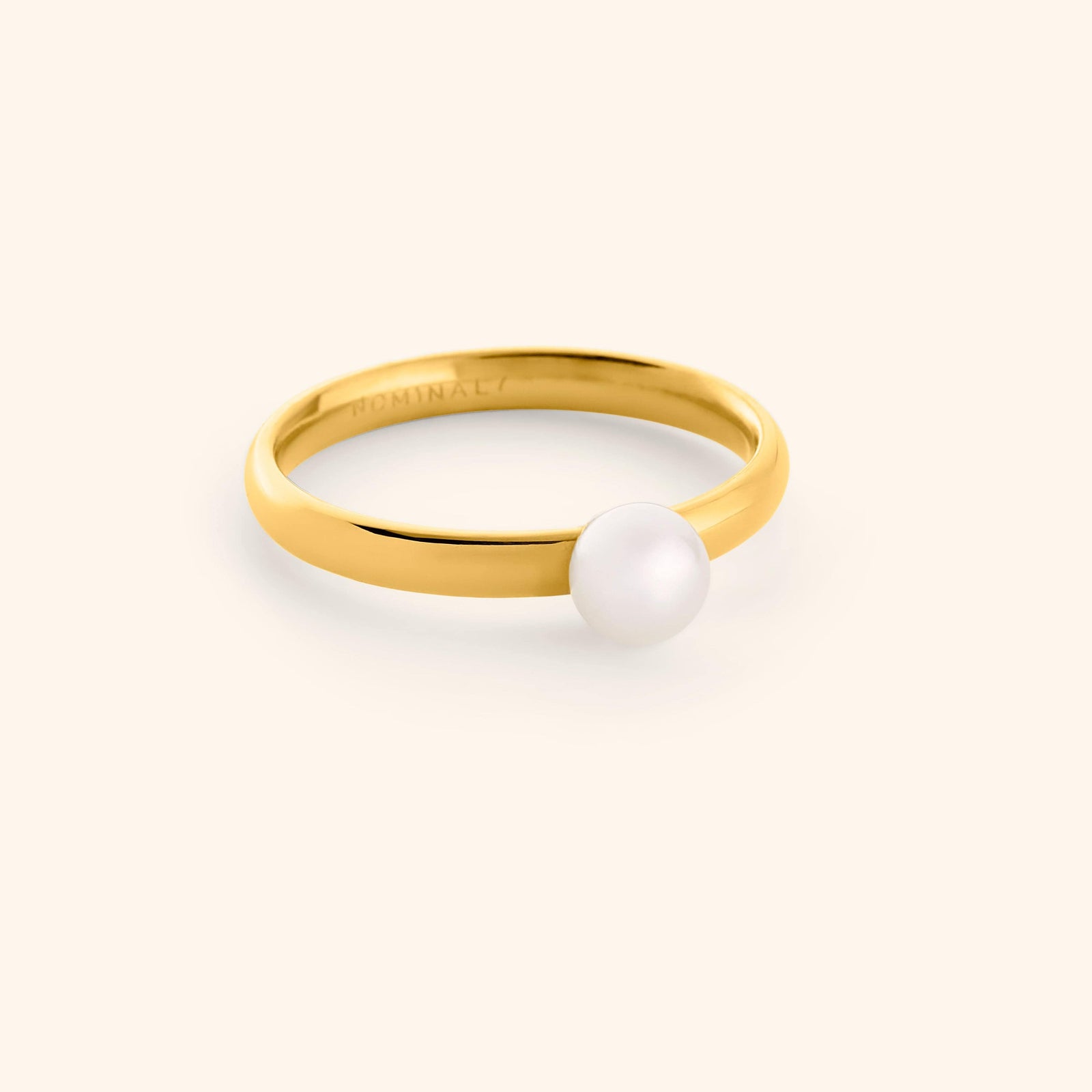 Gold ring with a pearl on a light background