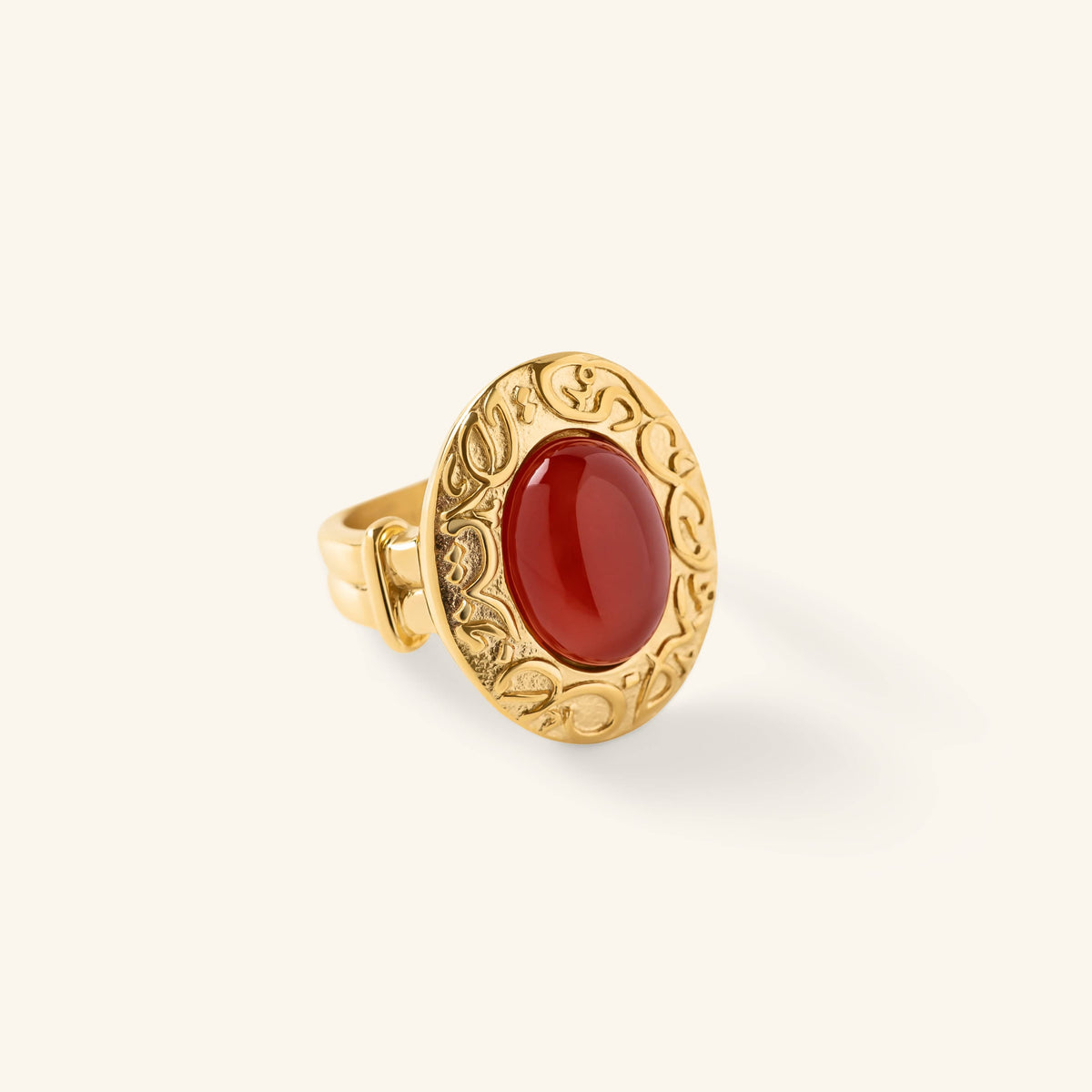 Gold ring with an oval red stone centered inside an engraved bezel featuring arabic calligraphy.