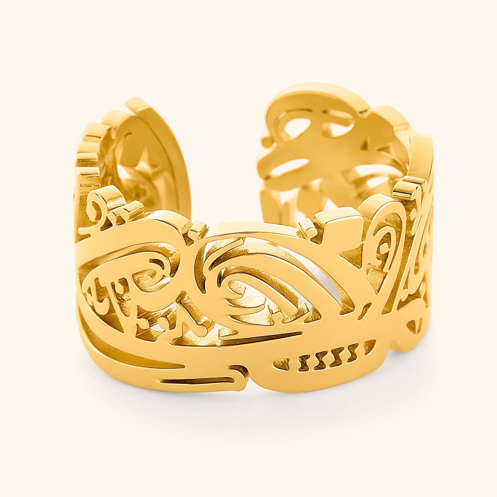 Gold Ease ring with intricate Arabic calligraphy cutout design, wide band with smooth polished edges, photographed against a light background.