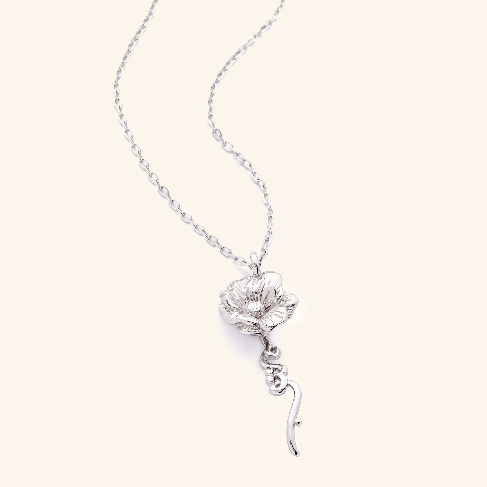A silver necklace with the anemone flower shaped pendant that features  Arabic word for ‘written’, curving in calligraphy out of the stem of the flower.