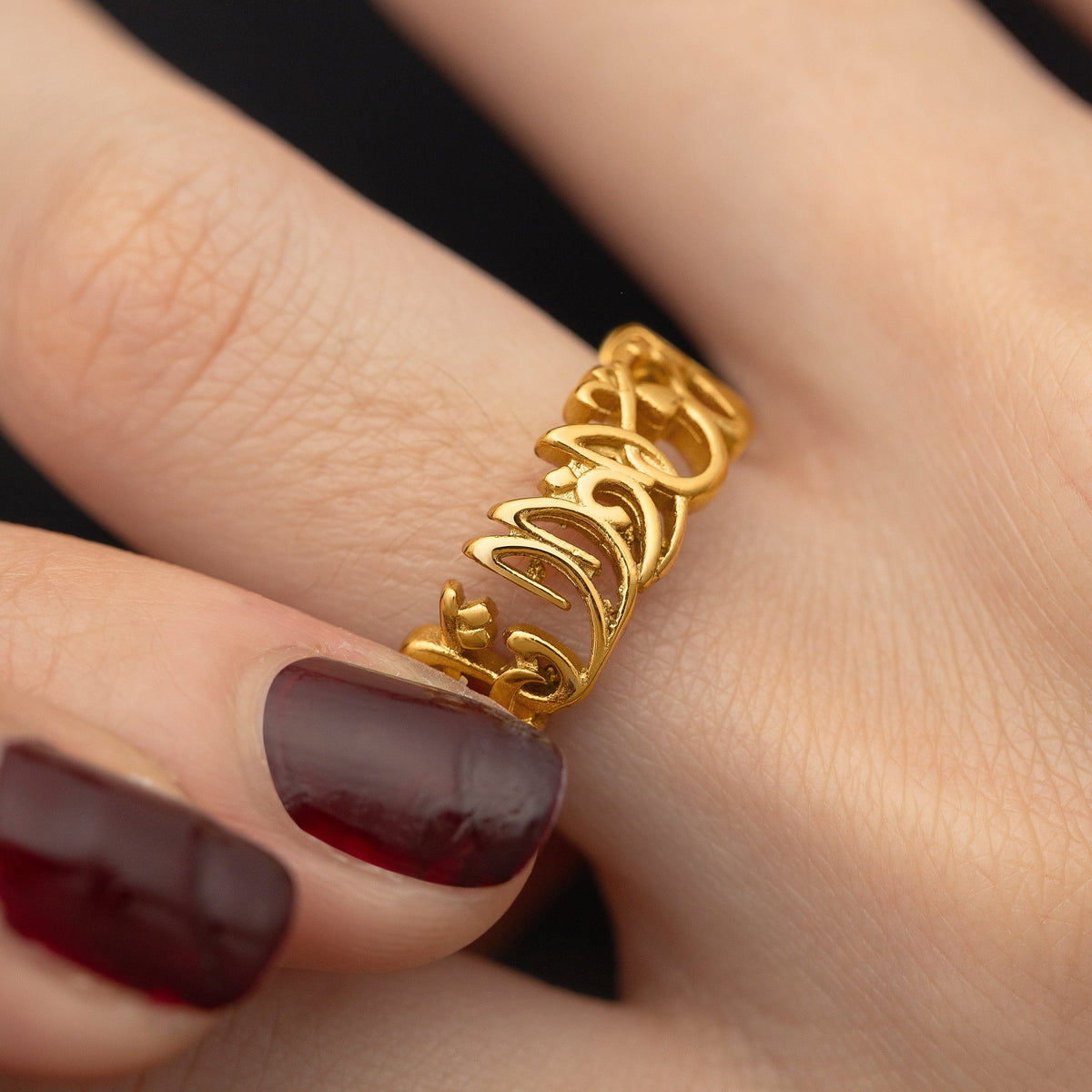 Close up of the gold "Walk to Me and I'll Run to You" Calligraphy ring worn and held by the model.