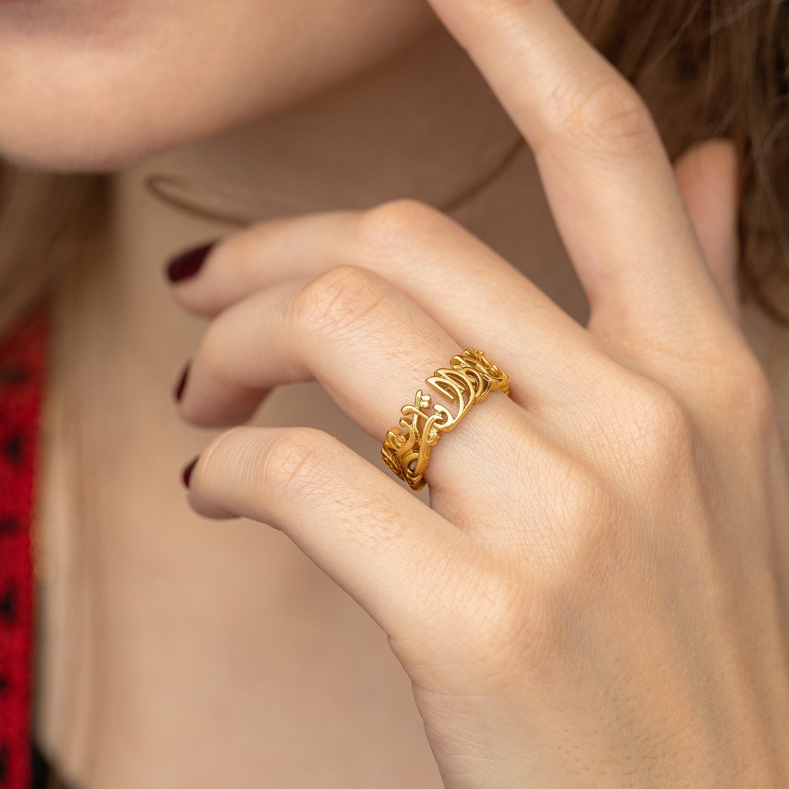 Close up photo of the gold ring worn on the model's left ring finger.
