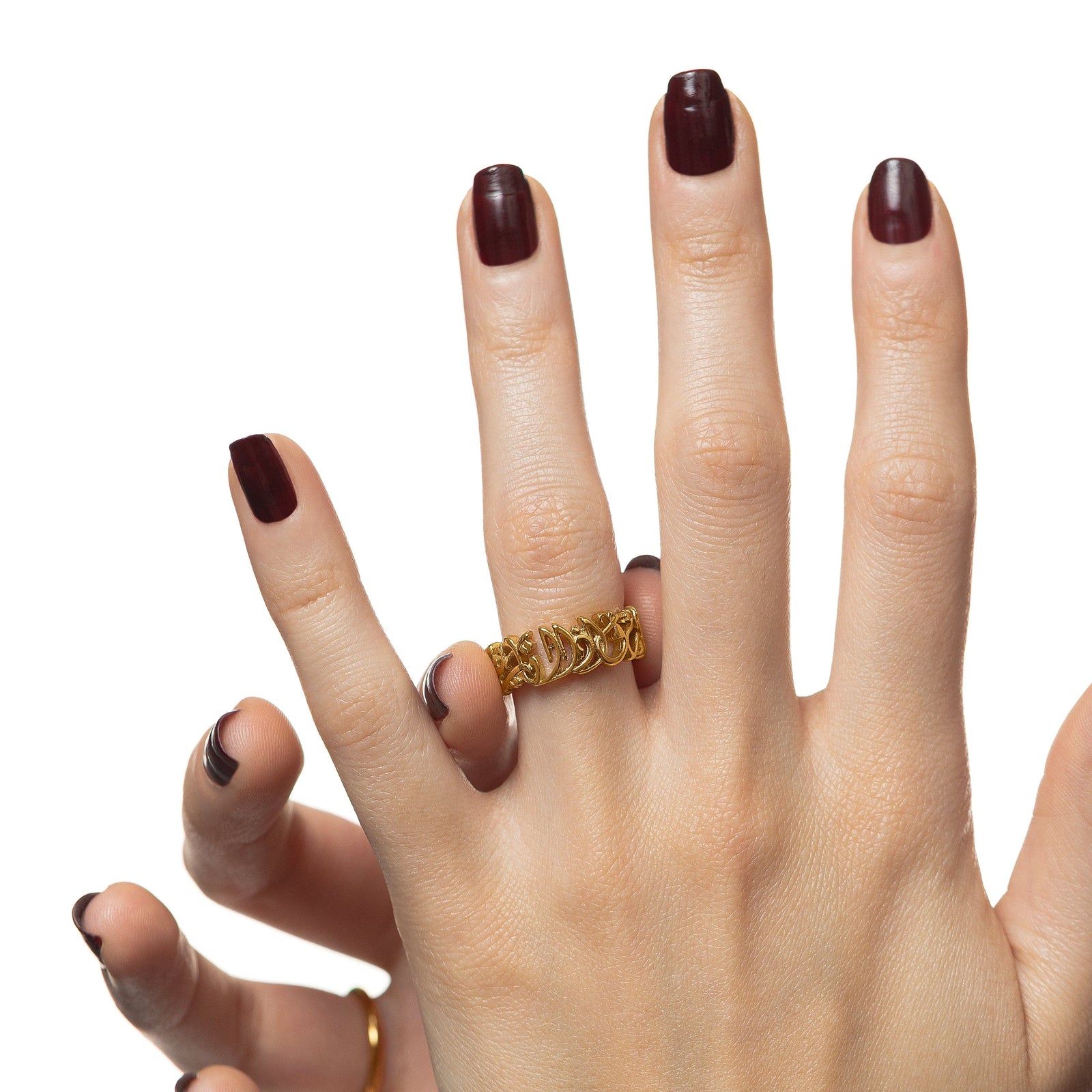 Photo of the model's left hand wearing the gold ring on their left ring finger. Model is also holding the ring with their thumb and right index finger.