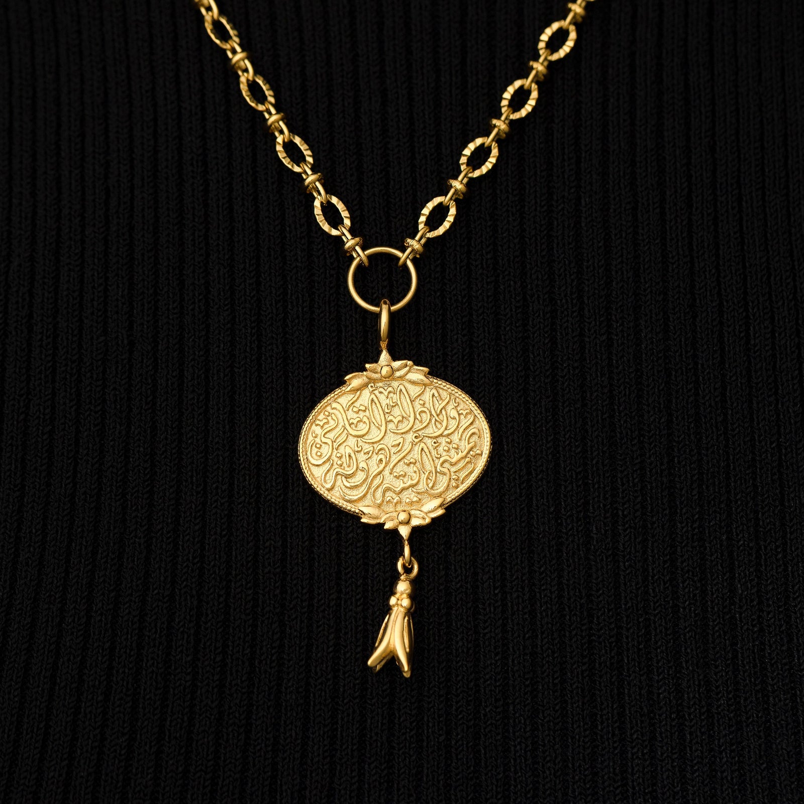 Close up photo of the gold pendant of the "Walk to Me, and I'll run to you" Medallion Necklace on black background.