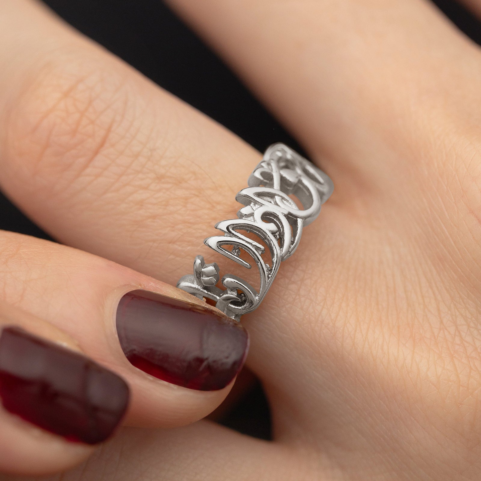 Close up of the silver "Walk to Me and I'll Run to You" Calligraphy ring worn and held by the model.