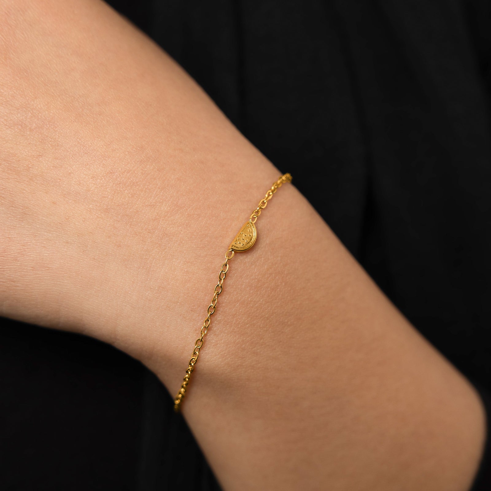 A model wearing the 18K gold-plated Watermelon Bracelet. The bracelet rests gracefully on her wrist, highlighting the subtle watermelon slice design against her skin.