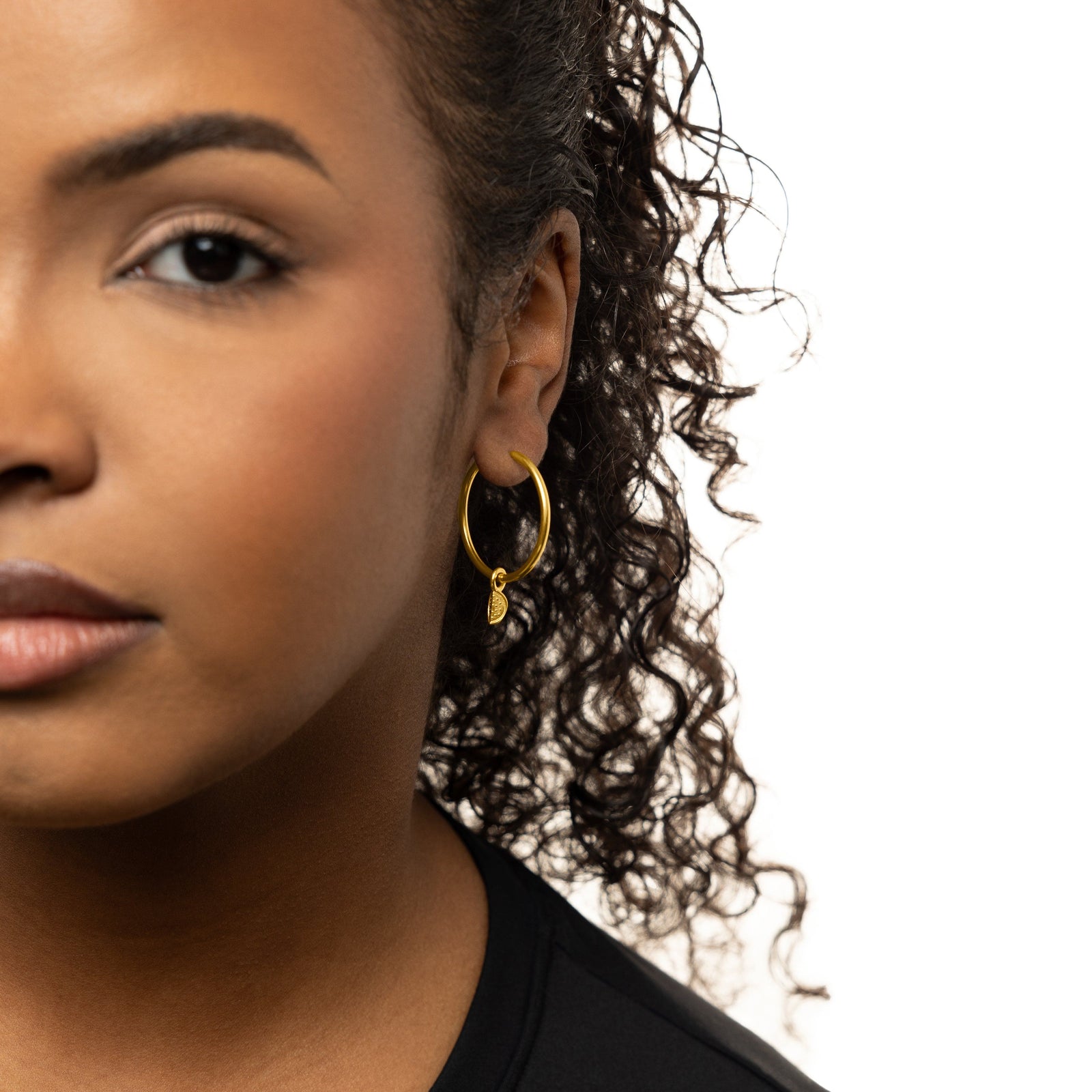 Photo of the model's left side of their face. The model is wearing a gold hoop earring with a gold Watermelon Earring Hoop Charm on their left ear.