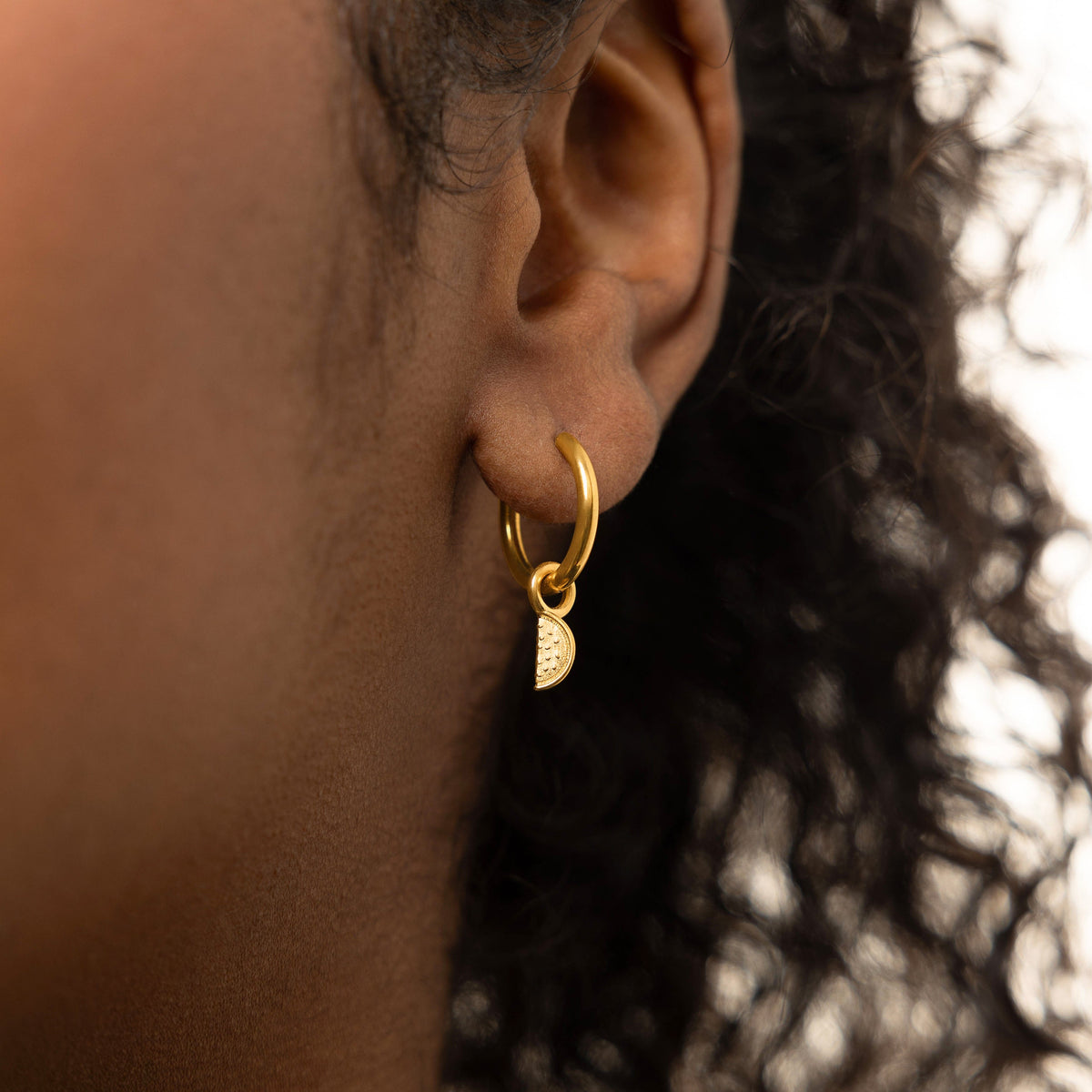 A model wearing the 18K gold-plated Watermelon Hoops. The earrings sit delicately on her earlobes, highlighting the vibrant watermelon design against her skin.