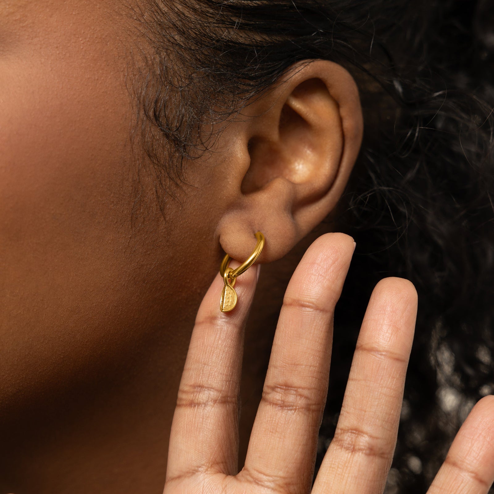 A model wearing the 18K gold-plated Watermelon Hoops. The earrings sit delicately on her earlobes, highlighting the vibrant watermelon design against her skin.