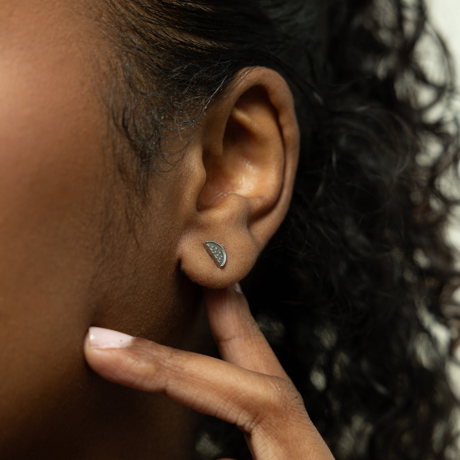 A model showcasing the silver Watermelon Studs. The earrings are positioned on her earlobes, emphasizing the colorful watermelon slice design against a neutral background.