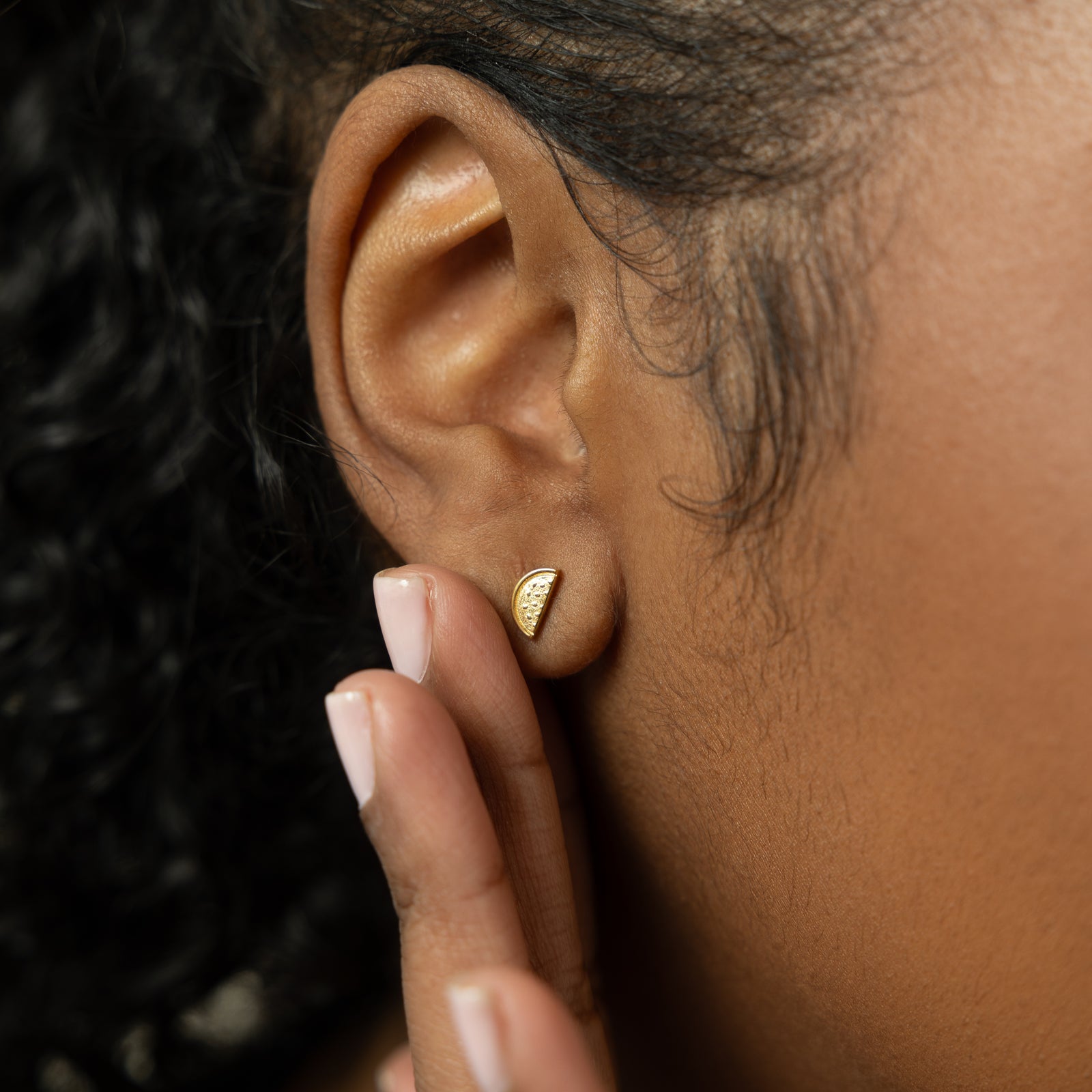 A model wearing the 18K gold-plated Watermelon Studs. The earrings sit delicately on her earlobes, highlighting the vibrant watermelon design against her skin.