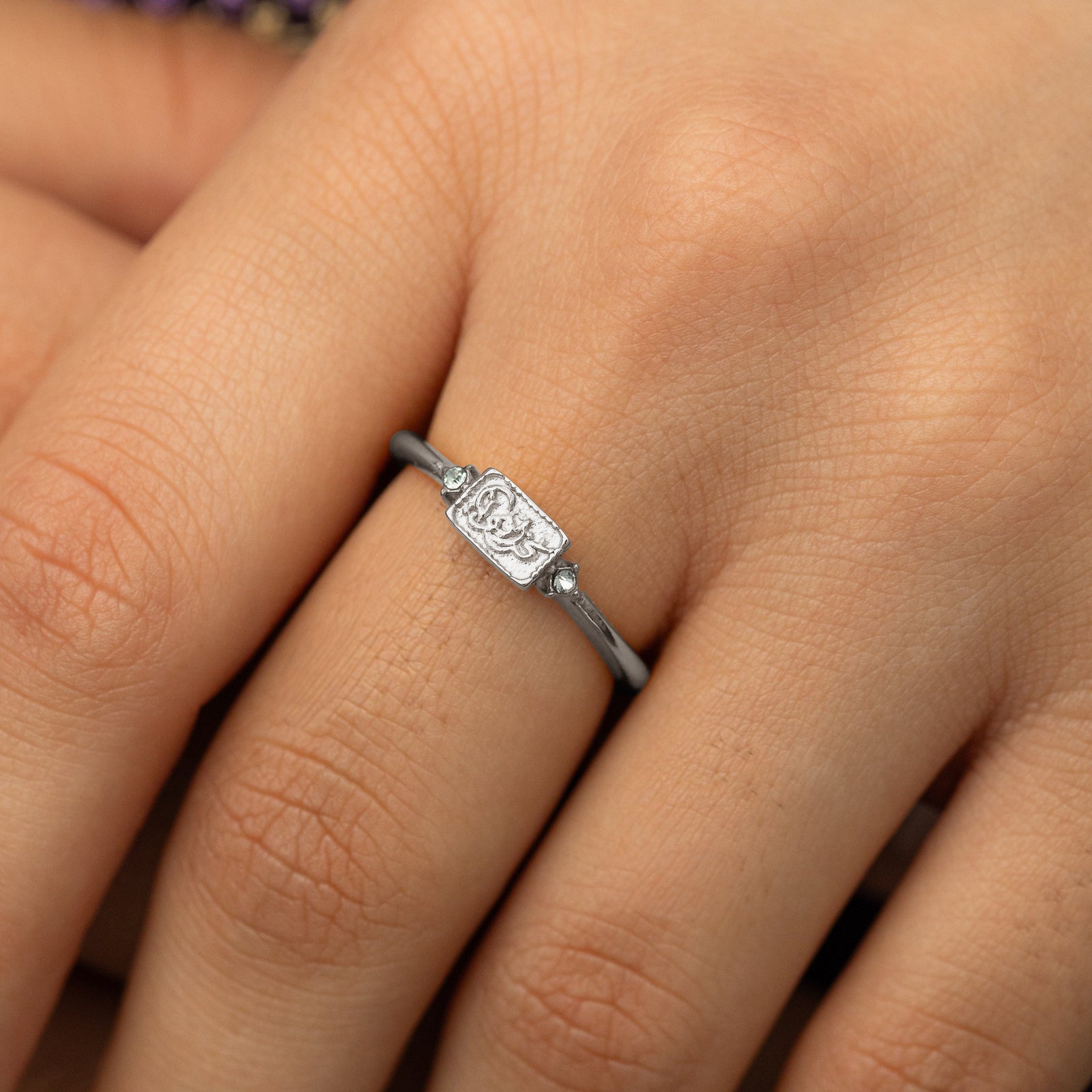Close up of the silver We Are Strong ring as the model wears it.