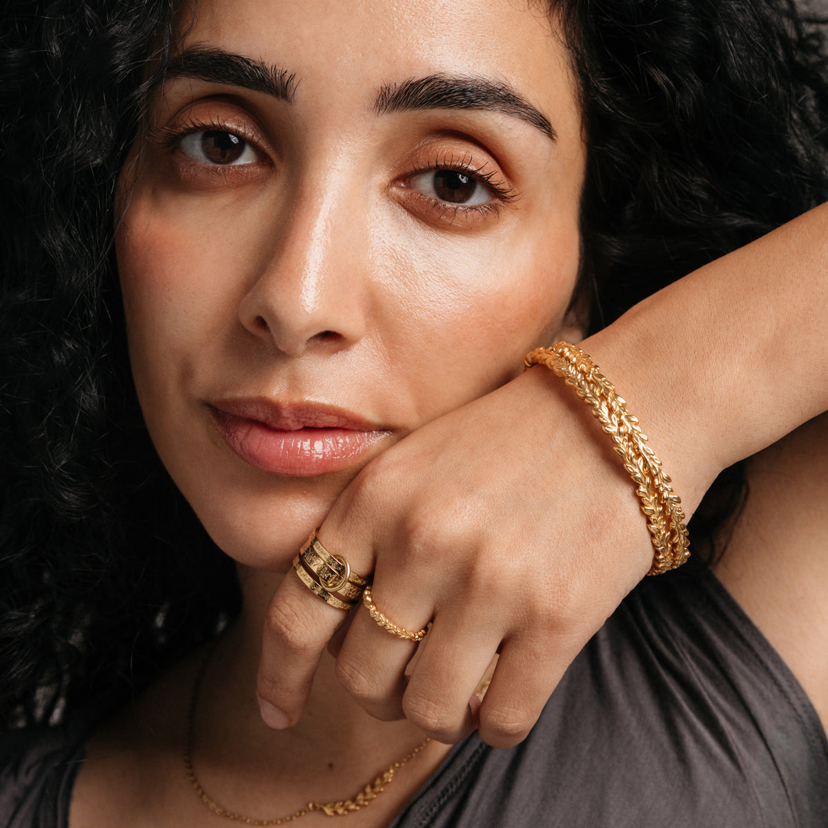 Model styled in 18k gold-plated Nominal jewelry featuring the Wrapped Olive Branch Ring paired with the Ayatul Kursi Ring Stack and stacked Weaving Olive Branch Bangles.