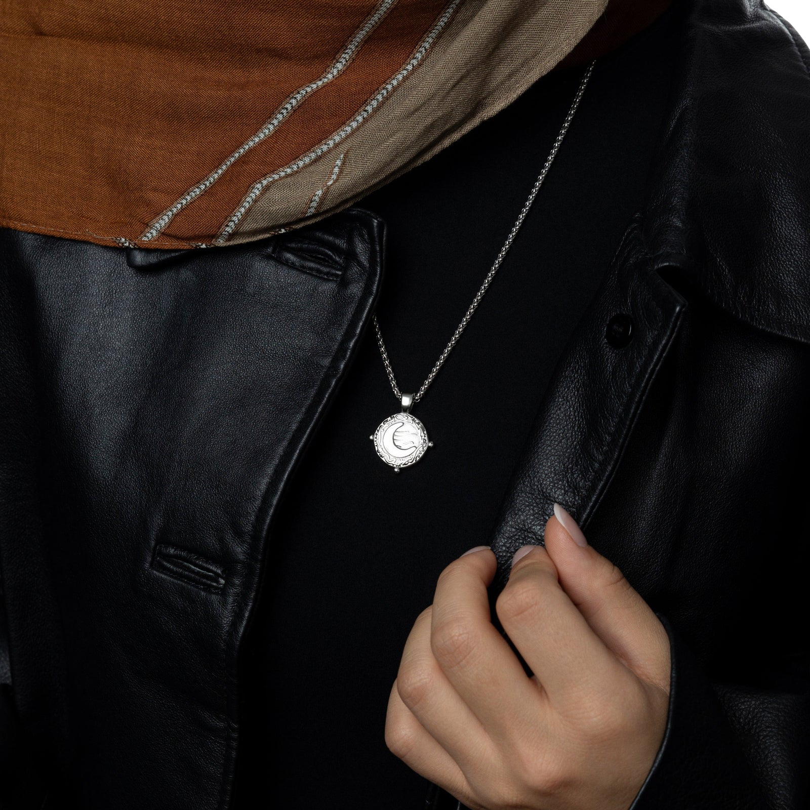 Silver what you seek is seeking youworn over a black top and leather jacket, styled with a taupe and rust hijab.
