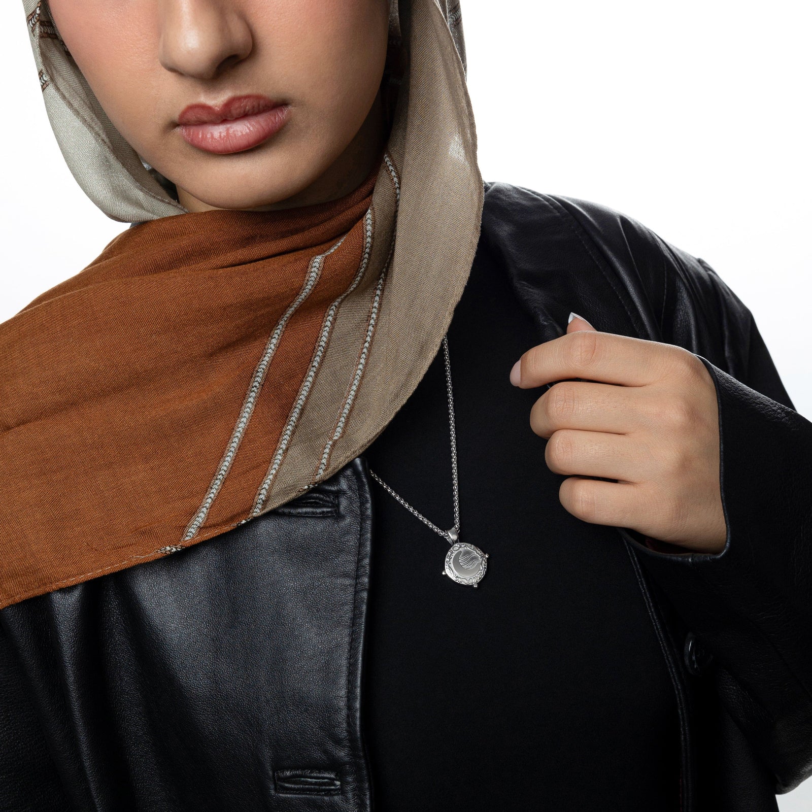 Silver what you seek is seeking youworn over a black top and leather jacket, styled with a taupe and rust hijab. 