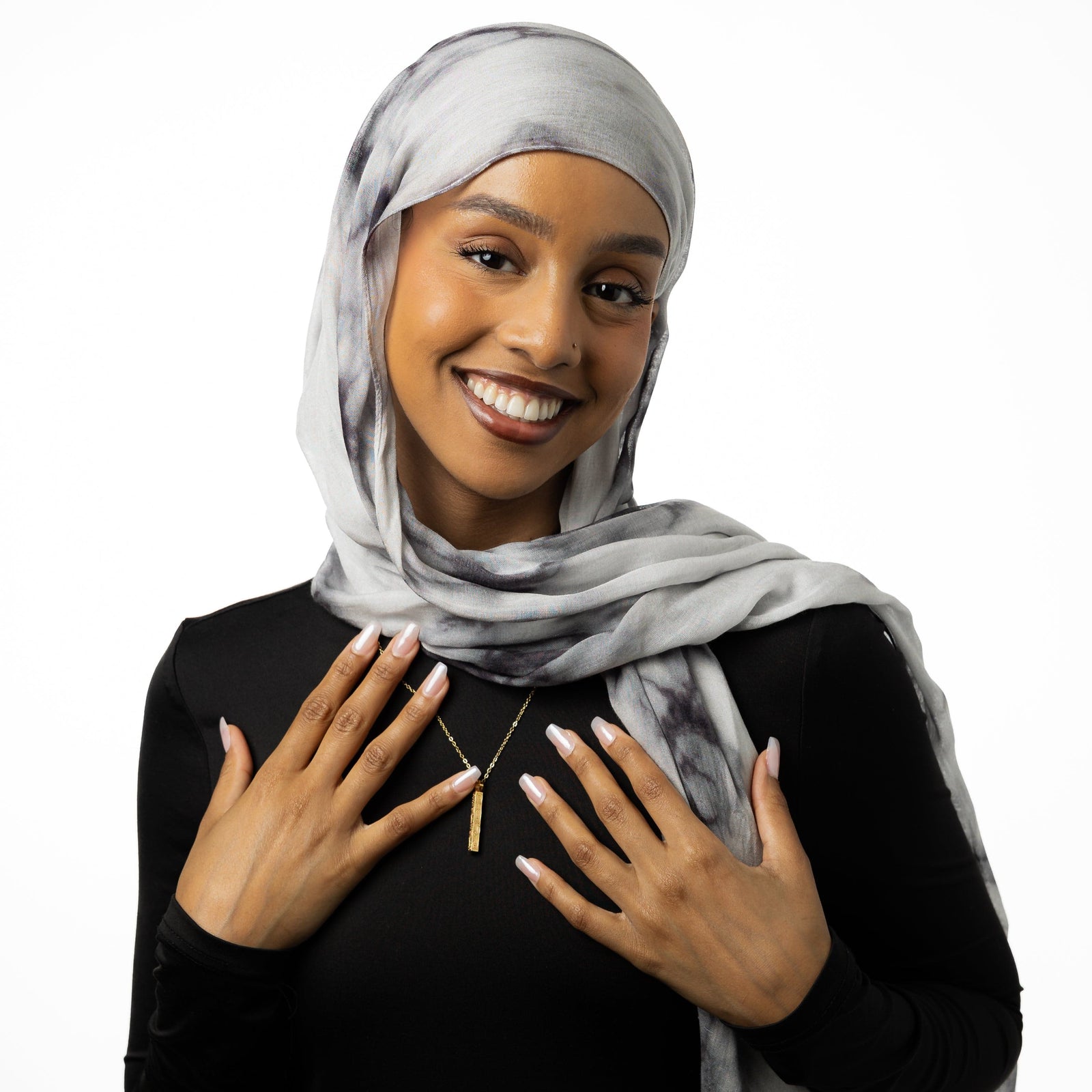 Photo of the model smiling to the camera. The model is wearing the gold "With Hardship Comes Ease" Bar Necklace.