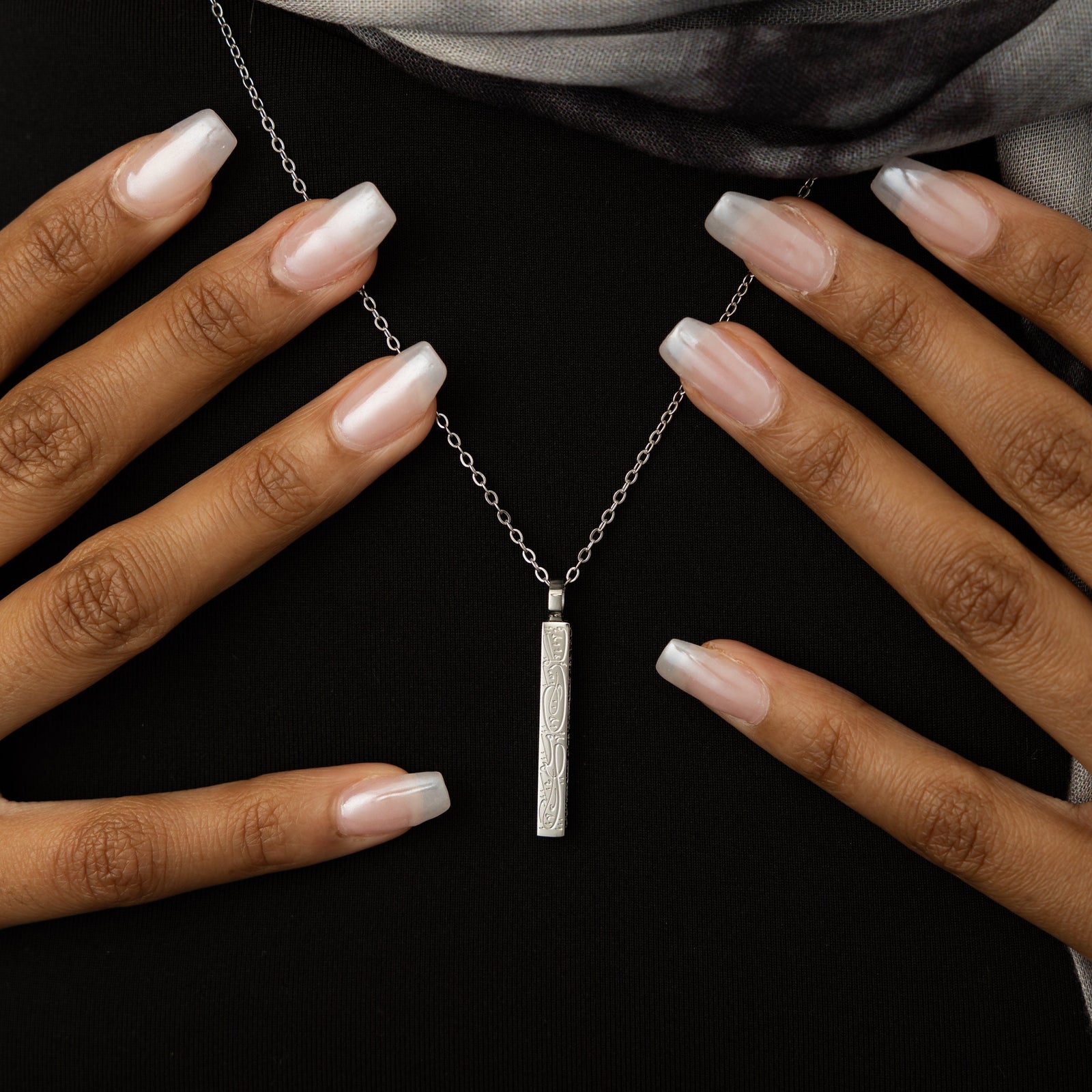 Close up of the silver "With Hardship Comes Ease" Bar Necklace as worn by the model.