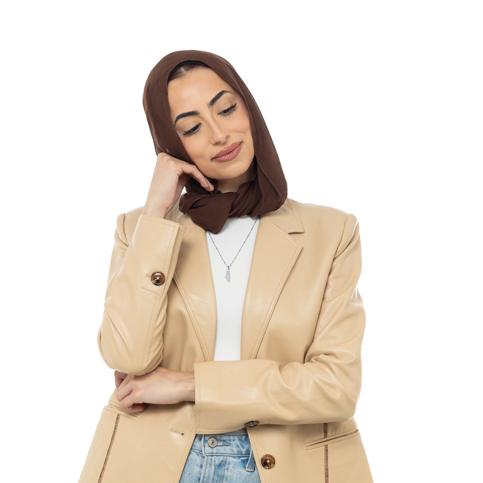A model wearing the 18K gold-plated "With Hardship Comes Ease" Map Necklace. The necklace rests gracefully on her collarbone, highlighting the map pendant with Arabic calligraphy against a neutral-toned outfit.